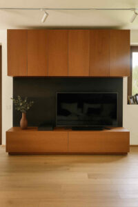 parete attrezzata moderna legno ciliegio, mobile soggiorno su misura legno, parete soggiorno elegante in legno, mobile TV con pensili alti, parete attrezzata legno frassino color ciliegio, arredo soggiorno moderno con pannello nero, mobili soggiorno artigianali, mobile TV design legno ciliegio, composizione soggiorno contemporanea, parete attrezzata made in Italy