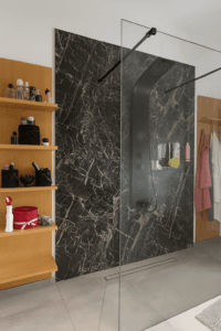 doccia design moderno, rivestimento bagno marmo nero, pannello doccia nero, arredo bagno elegante, mensole in legno bagno, bagno contemporaneo
